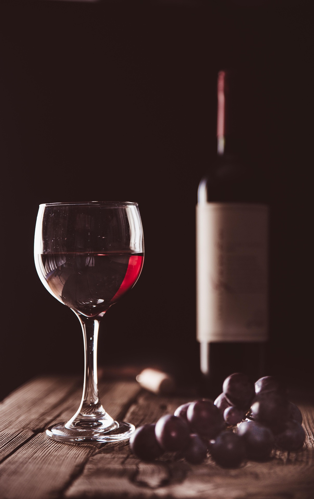 Glas Rotwein mit Flasche und Trauben