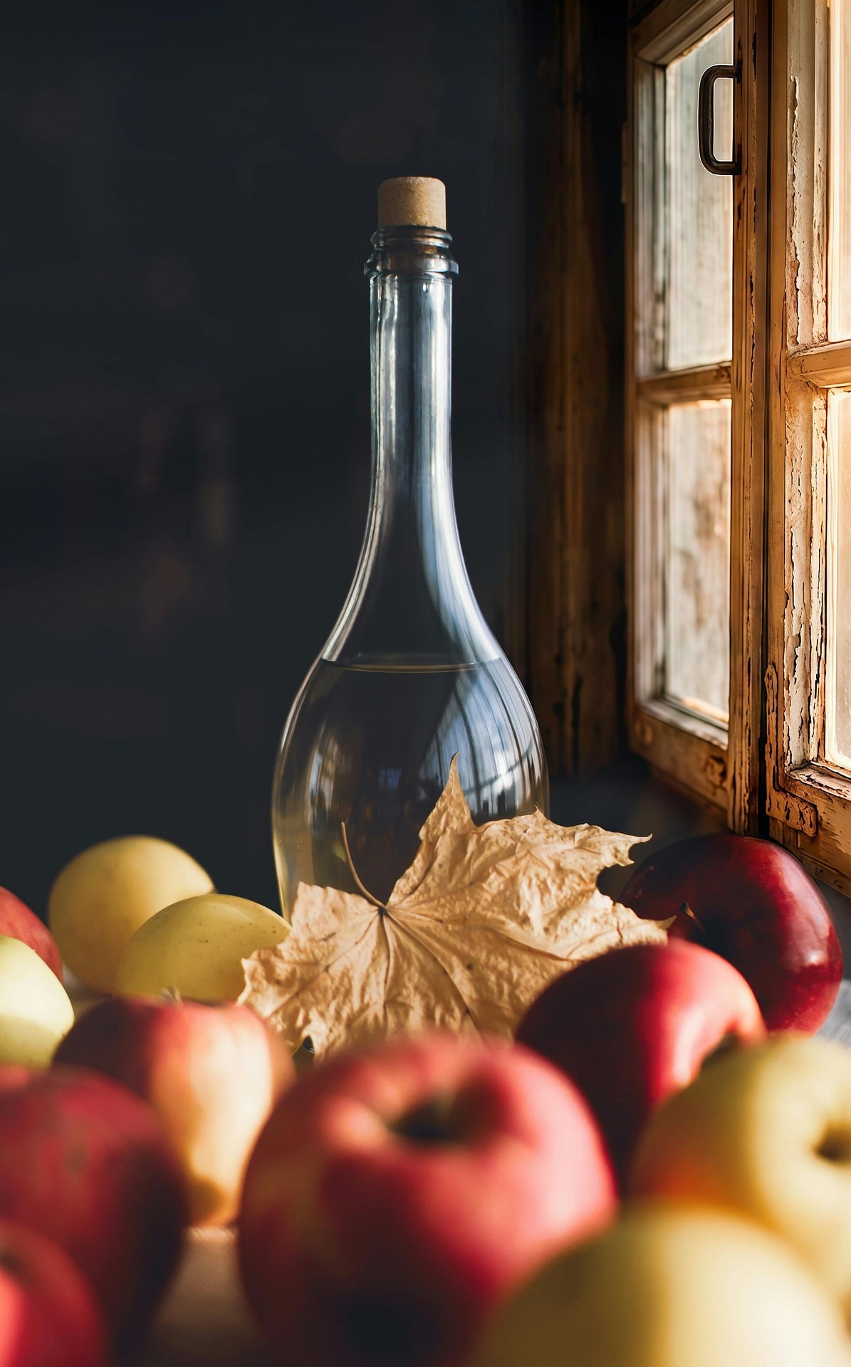 Flasche am Fenster mit Äpfeln